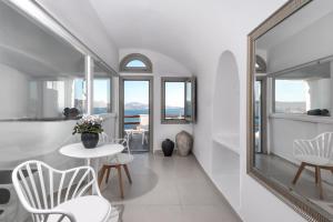 Habitación blanca con espejo, mesa y sillas en Caldera Premium Villas en Oia