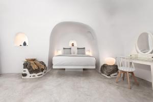 Dormitorio blanco con cama y tocador en Caldera Premium Villas en Oia