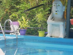 a statue of a person sitting next to a swimming pool at Hotel Cafe Del Mar, En Valle Pura Vida in Manuel Antonio