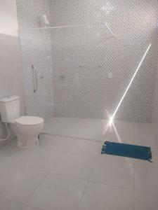 a white bathroom with a shower and a toilet at Flor de Mandacaru Pousada in Boqueirão (1)