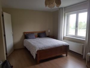 una camera da letto con un letto con cuscini blu e una finestra di B&B Wijnendalvallei a Torhout