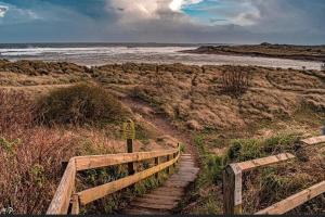 un conjunto de escaleras que conducen a una playa con un cartel en Westlea Guest House, en Alnmouth