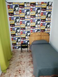 a room with a bed, chair and a wall at Alcaravaneras Hostel in Las Palmas de Gran Canaria