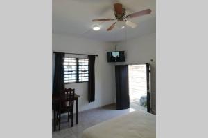 a bedroom with a ceiling fan and a table at Maruchita's room in Bacalar