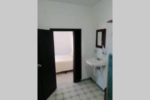 ein Bad mit einem Waschbecken und eine Tür, die zu einem Schlafzimmer führt in der Unterkunft Maruchita's room in Bacalar