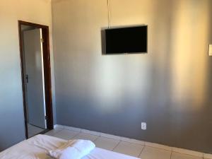 een slaapkamer met een flatscreen-tv aan de muur bij POUSADA GIRASSOL in Saquarema