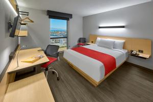 Heroica CaborcaにあるCity Express by Marriott Caborcaのベッド、デスク、窓が備わるホテルルームです。