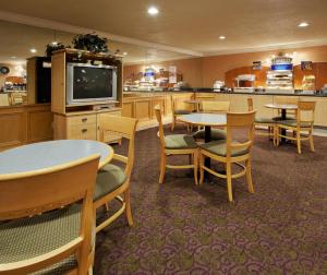 a restaurant with tables and chairs and a television at Holiday Inn Express Hotel Union City San Jose, an IHG Hotel in Union City