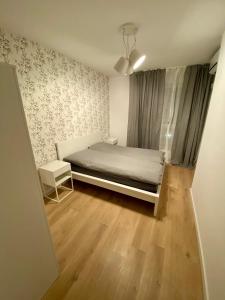 a small bedroom with a bed and a wooden floor at Panoramic view apartments Warsaw West II in Warsaw