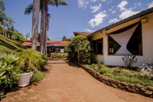 a brick walkway leading to a house with palm trees at Villa Garibaldi in Joanópolis