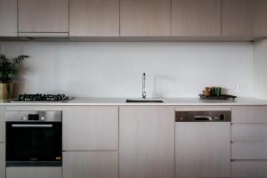 a kitchen with white cabinets and white appliances at Nishi Apartments Eco Living by Ovolo in Canberra