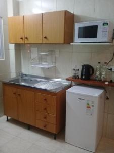 a kitchen with a sink and a microwave and a refrigerator at Monoambiente Residencial in San Carlos de Bariloche