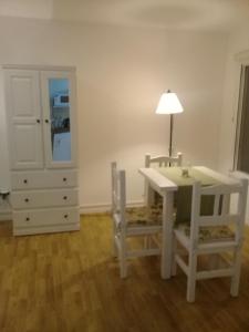 a white table and chairs with a lamp and a dresser at Monoambiente Residencial in San Carlos de Bariloche