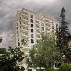 ein hohes weißes Gebäude mit Bäumen davor in der Unterkunft Central Luxury Apartment in Pristina