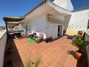 une terrasse avec des chaises et une table sur une maison dans l'établissement Apartamento Las Infantas. Centro de Sanlucar., à Sanlúcar de Barrameda