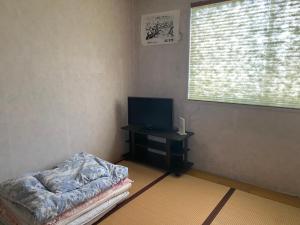 een woonkamer met een tv en een tafel met een bed bij Oyado Sukeya in Saijo