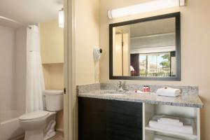 a bathroom with a sink and a toilet and a mirror at Days Inn by Wyndham Clearwater/Central in Clearwater