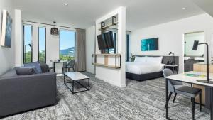 a hotel room with a bed and a living room at Oaks Cairns Hotel in Cairns