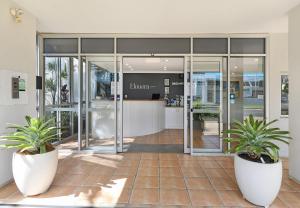 uma entrada para um edifício com dois vasos de plantas em Elouera Tower em Maroochydore