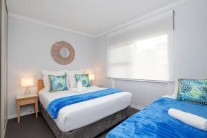 
a bedroom with a bed, desk, and nightstand at Glenelg Oasis Studios in Adelaide
