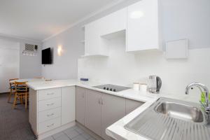 
a kitchen with a sink, stove, dishwasher and cabinets at Glenelg Oasis Studios in Adelaide
