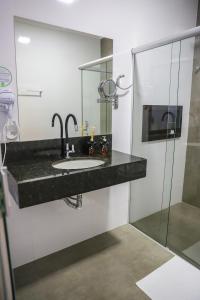 uma casa de banho com um lavatório e uma cabina de duche em vidro. em POUSADA JURERE DA CANASTRA em Vargem Bonita