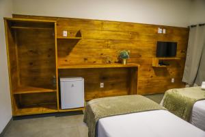a bedroom with two beds and a wooden wall at POUSADA JURERE DA CANASTRA in Vargem Bonita