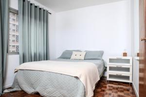a white bedroom with a bed and a window at Vila Olimpia Jade in São Paulo
