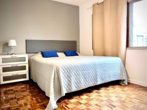um quarto com uma cama com almofadas azuis e uma janela em Vila Olímpia Colors em São Paulo
