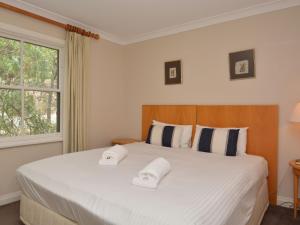 1 dormitorio con 1 cama blanca grande y 2 toallas en Villa 3br Chambourcin Villa located within Cypress Lakes Resort, en Pokolbin