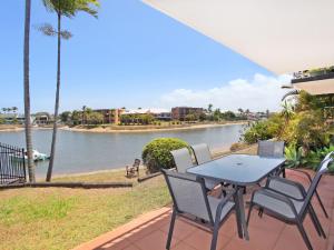 a table and chairs on a patio overlooking a river at Courtney Cove 1 Comfortable Two Bedroom Apartment on Mooloolaba Canal in Mooloolaba