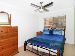 a bedroom with a bed and a dresser and a ceiling fan at Courtney Cove 1 Comfortable Two Bedroom Apartment on Mooloolaba Canal in Mooloolaba