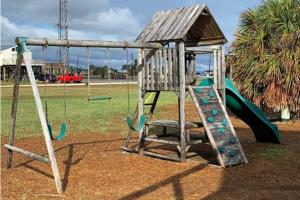 a playground with a slide and a swing at Salty Poodle Cottage in Freeport