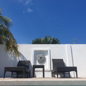 drie stoelen en een klok op een witte muur bij Liquid Dive Resort in Dauin