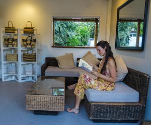 a woman sitting on a couch reading a book at Liquid Dive Resort in Dauin