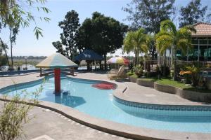 een zwembad met een parasol en een tafel bij RedDoorz Plus @ Rio Grande de Laoag Resort Hotel Ilocos Norte in Laoag