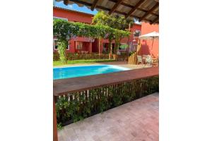 a pool with a wooden bench next to a house at Ecoville das Mangueiras - Condomínio em Monte Gordo - Região de Guarajuba in Monte Gordo