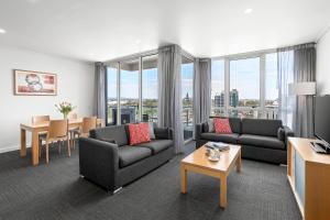 een woonkamer met 2 banken en een tafel en stoelen bij Quest Southbank in Melbourne