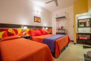 a bedroom with two beds with orange and purple at Hotel Calimera in Santa Teresita