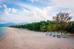 una playa de arena con sillas y sombrillas. en Khanom Sea Beach Resort, en Nakhon Si Thammarat