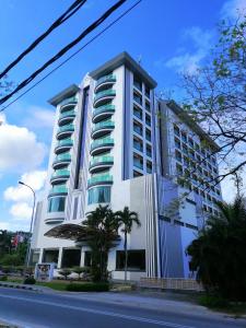 a tall white building with palm trees in front of it at Langkawi Seaview Hotel in Kuah
