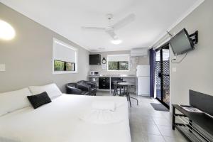 a bedroom with a white bed and a kitchen at BIG4 Cane Village Holiday Park in Bundaberg