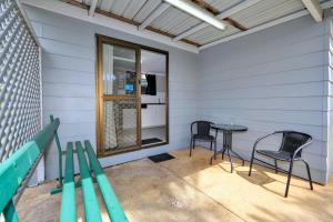 eine Terrasse mit 2 Stühlen, einem Tisch und einem Fenster in der Unterkunft BIG4 Cane Village Holiday Park in Bundaberg