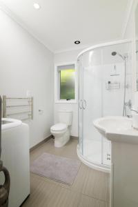 a white bathroom with a shower and a toilet at Fabulous Apartment with Private Spa Pool & Gym in Picton