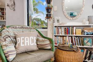 Habitación con silla, mesa y espejo. en Waipu Cove Palm Cottage - Waipu Cove Holiday Home en Waipu
