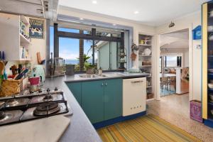 eine Küche mit Spüle und Herd oberen Backofen in der Unterkunft Waipu Cove Palm Cottage - Waipu Cove Holiday Home in Waipu