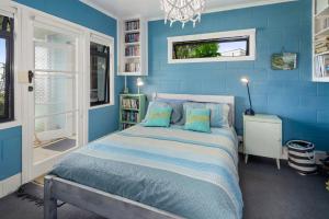 ein blaues Schlafzimmer mit einem Bett mit blauen Wänden in der Unterkunft Waipu Cove Palm Cottage - Waipu Cove Holiday Home in Waipu