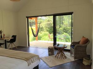 a bedroom with a bed and a sliding glass door at The Hideout in Mangawhai
