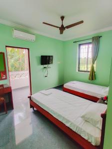 two beds in a room with green walls at Hotel Siesta De Goa in Varca