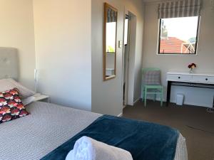 1 dormitorio con cama, escritorio y espejo en The Villa, en Picton